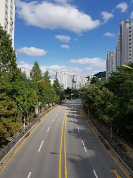 Aerial view of an empty street surrounded by lush green trees and urban high-rises in Yongin City, South Korea.